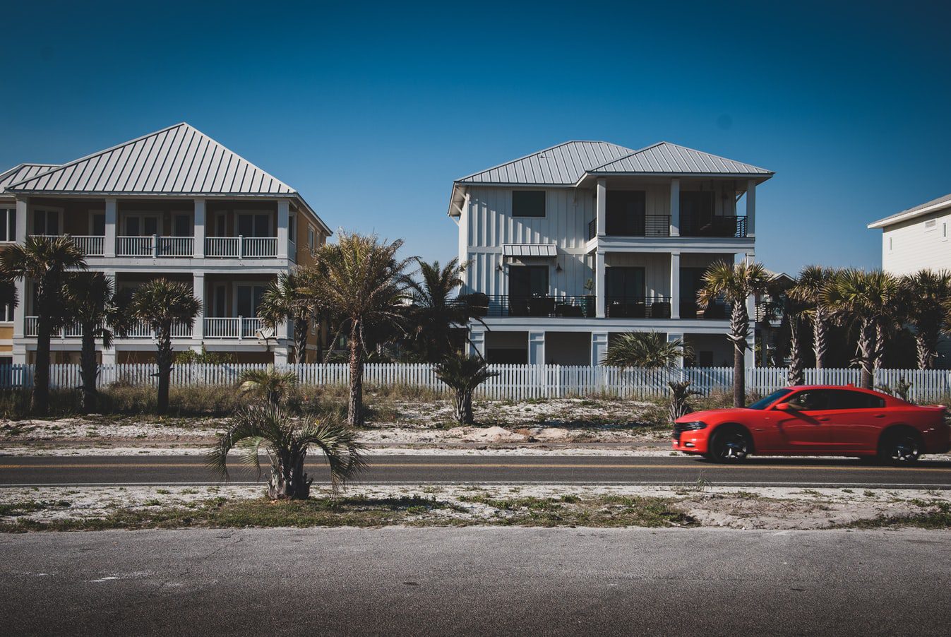 A red sports car outside two apartment buildings, where one might benefit from property management in Coral Springs by Florida Management & Consulting Group